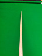 A close-up of a wooden snooker cue shaft pointing vertically upwards against a green snooker table felt background.