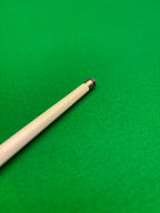 A close-up of a snooker cue shaft resting on a bright green felt table surface.