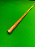 A wooden snooker cue with a natural wood finish and a small circular Pro Edge logo near the butt, resting diagonally on a bright green snooker table felt.