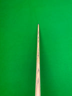 Close-up of a wooden snooker cue shaft pointing upward against a bright green felt table background.