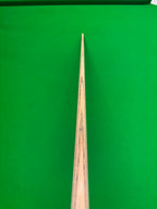 A close-up of a wooden snooker cue shaft pointing vertically down the center of a green snooker table.