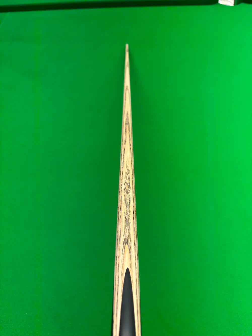 Close-up of a wooden snooker cue laying on a snooker table