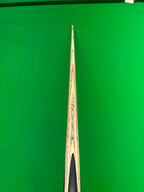 Close-up of a wooden snooker cue laying on a snooker table