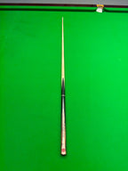 A single snooker cue laid vertically on a green snooker table, with the tip pointing toward the top edge of the frame.