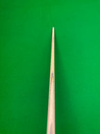 A close-up vertical shot of a wooden snooker cue shaft against a bright green felt background.