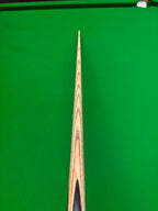 A close-up, top-down view of a wooden snooker cue shaft resting vertically on a green snooker table.