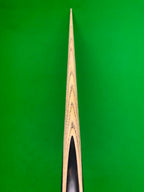 Close-up of a wooden snooker cue against a bright green felt background.