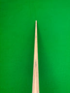 Close-up of a wooden snooker cue shaft pointing upward toward a bright green snooker table felt surface.