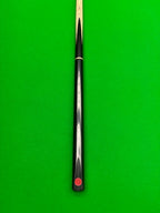 A close-up of a snooker cue shaft with a black handle and a red Pro Edge logo near the butt, set against a bright green snooker table felt background.
