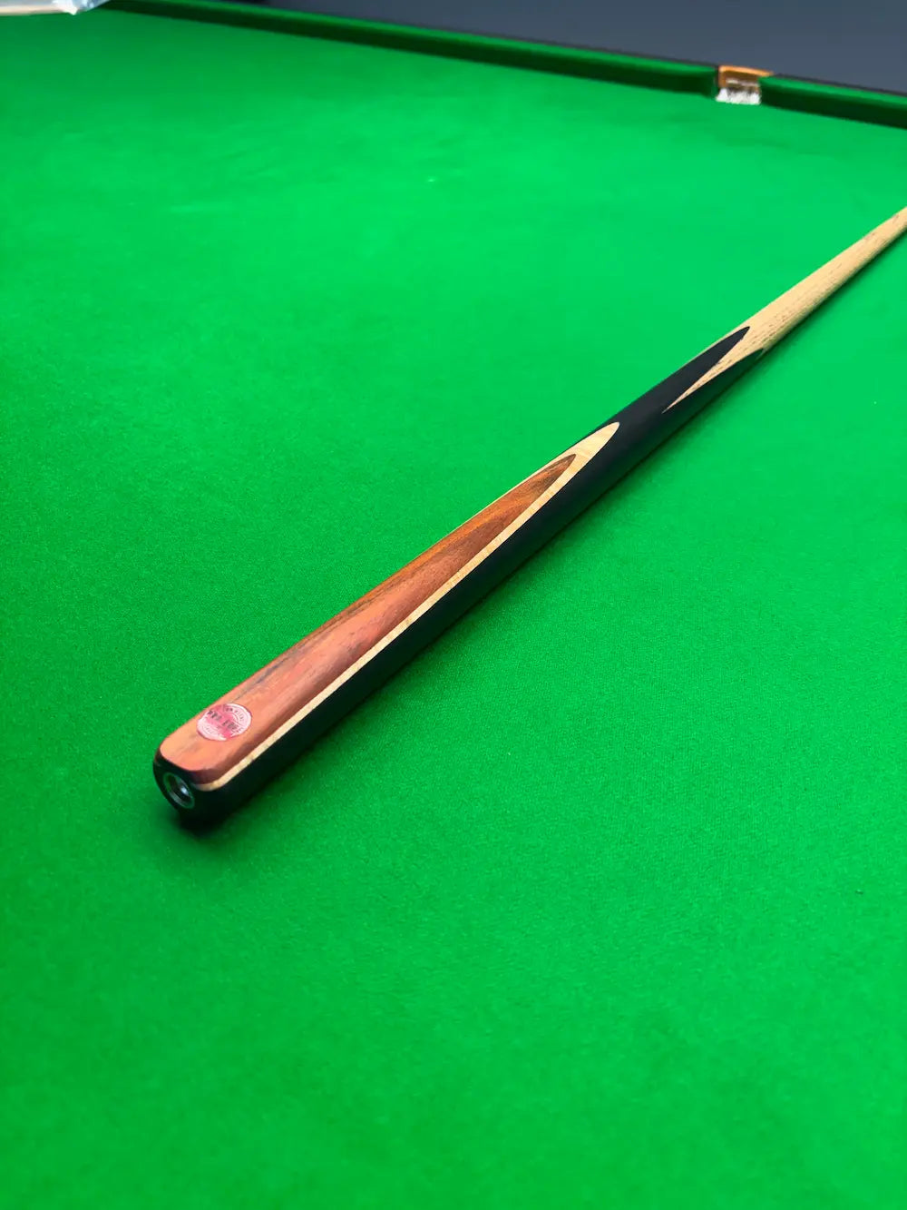 Ash snooker cue with a brass ferrule on a snooker table