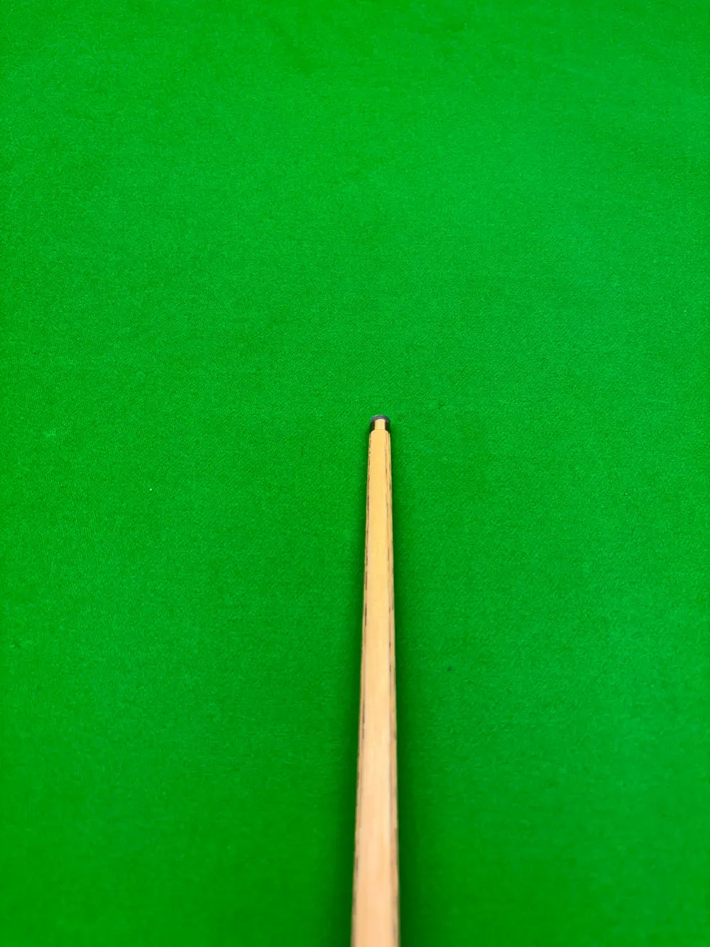 The brass tip of a Pro Edge Snooker cue on a snooker table 