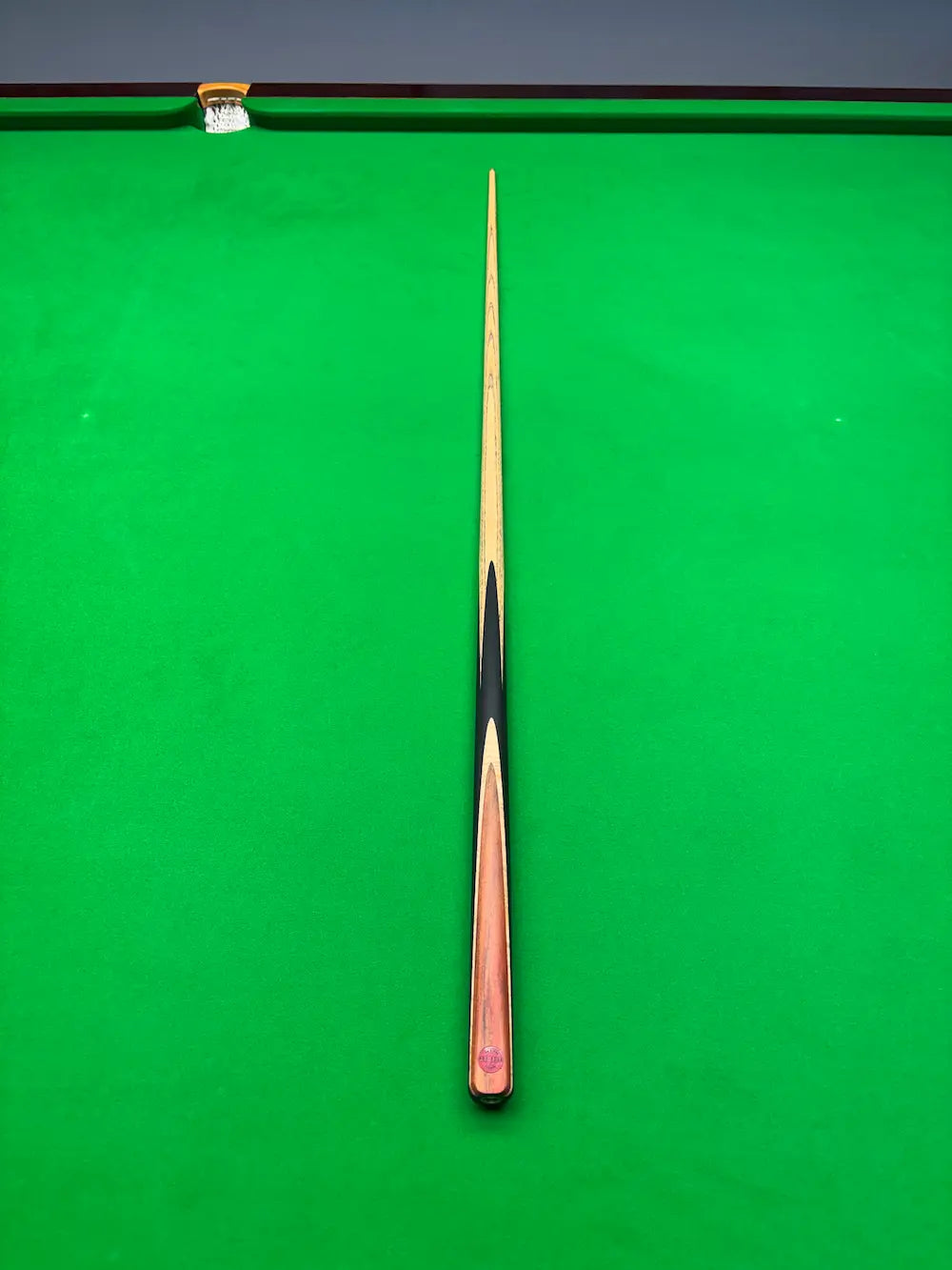 Ash snooker cue with a brass ferrule on a snooker table
