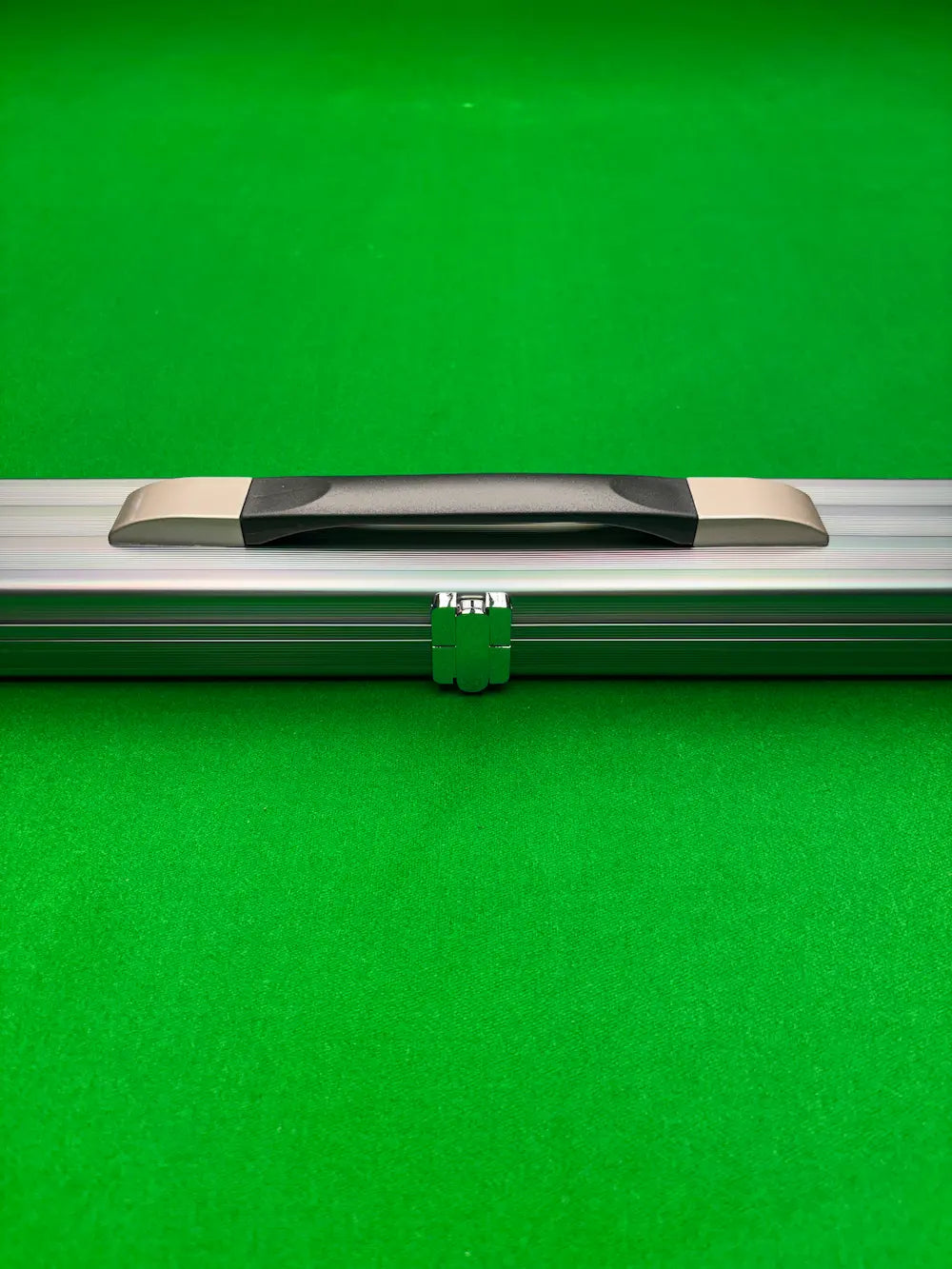 A closeup of a silver snooker cue case on a green cloth