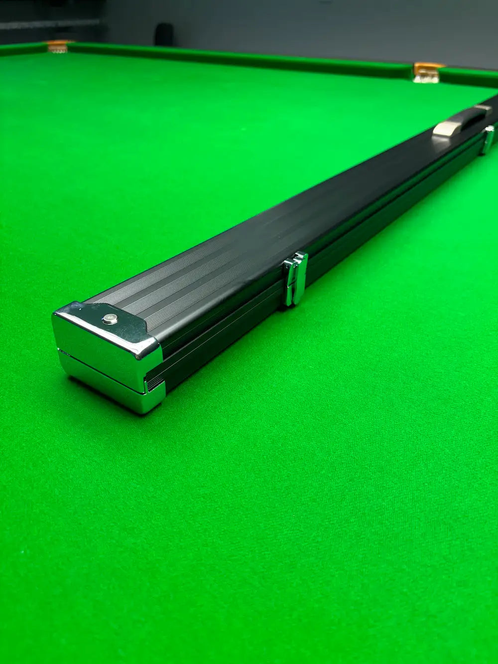 Black snooker cue case on a green snooker table