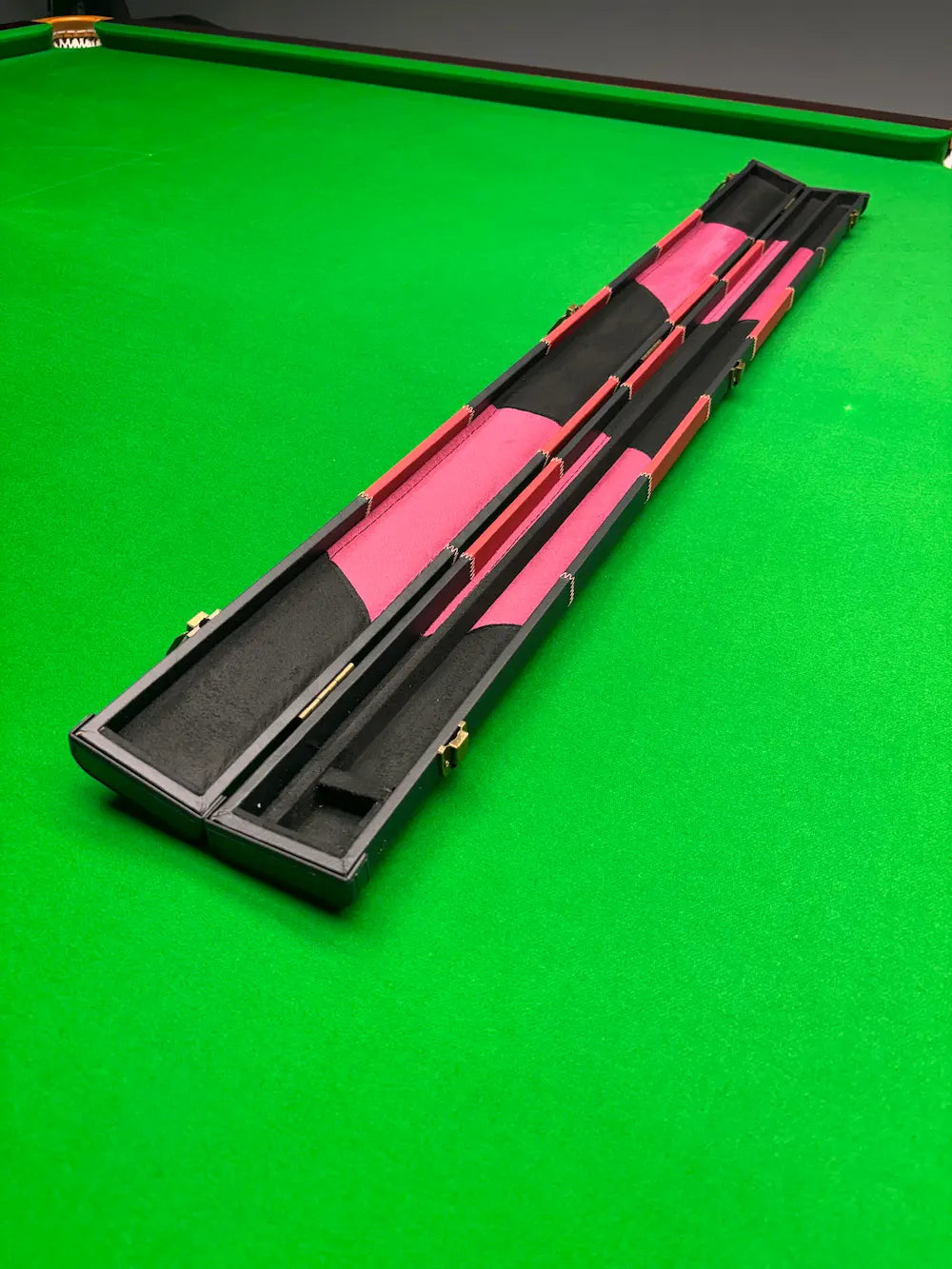 red and black snooker cue case on a green table