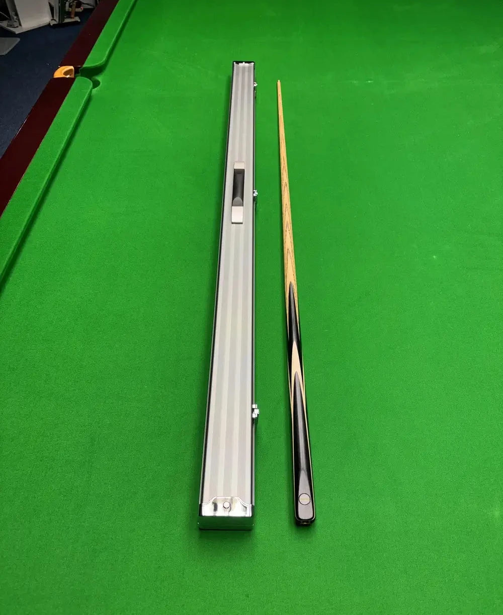 Pro Edge Precision ash snooker cue with grey aluminium cue case resting on a green snooker table