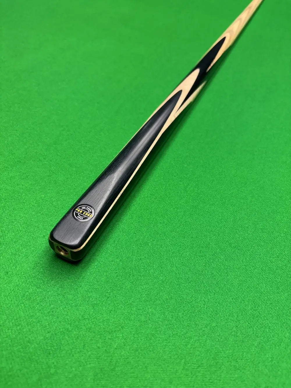 Pro Edge Precision Cue resting on a green snooker table, showcasing sleek design and professional craftsmanship.