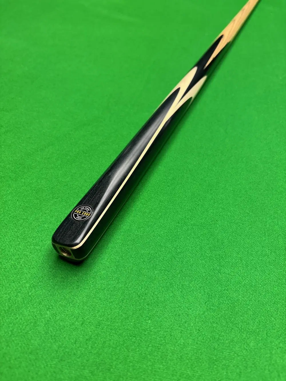 Pro Edge Precision ash snooker cue resting on a green snooker table