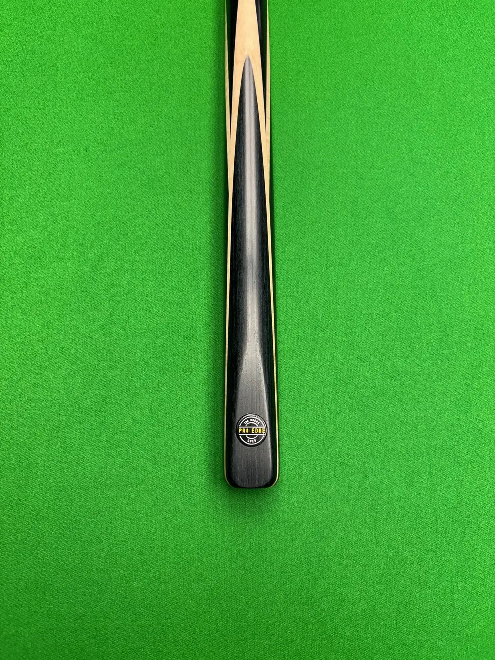 Pro Edge Precision Cue resting on a green snooker table, showcasing sleek design and professional craftsmanship.