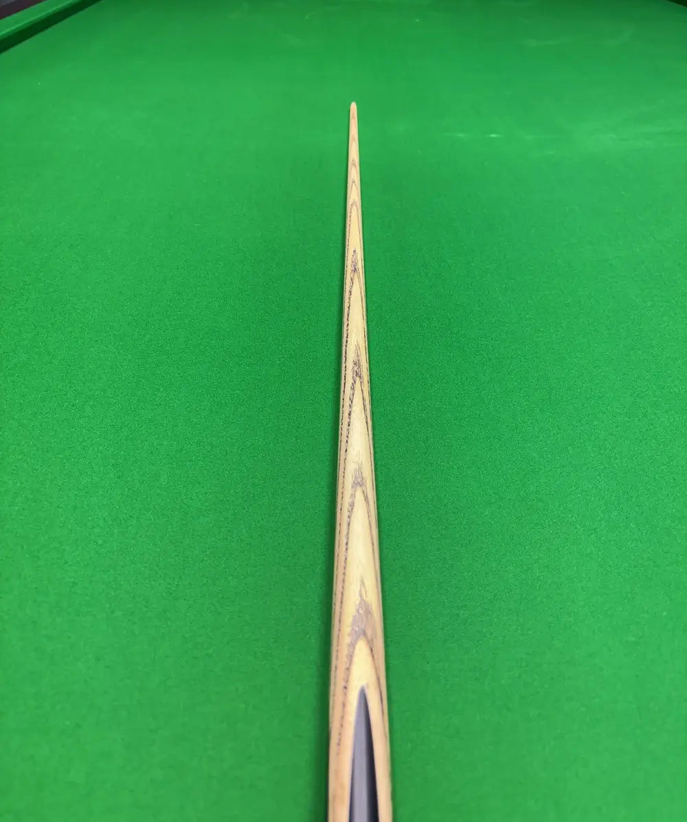 Pro Edge Precision Cue resting on a green snooker table, showcasing sleek ash design and professional craftsmanship.