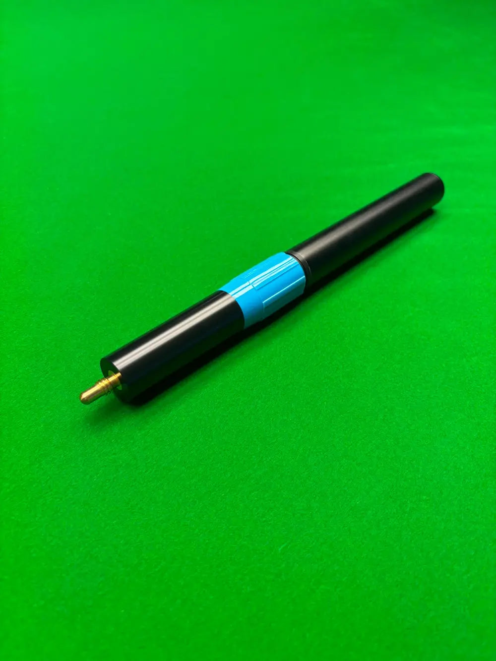 A black snooker cue extension with a bright blue band and a gold-colored tip, resting diagonally on a green felt surface.