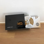 Cue balm packaging with black box and white container on a wooden surface